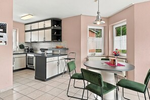A modern kitchen with a central island, built-in cabinets, and a dining area with a round table and green chairs.