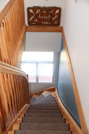 Una escalera de madera con una pared azul y una ventana con cortinas.