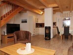 A living room with a brown leather sofa, a wooden coffee table, a TV, and a fireplace. - Aloha - Aloha in Greetsiel: 3 bedrooms, wood-burning stove, garden and WLAN (Krummhörn)