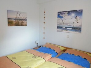 Ein Schlafzimmer mit zwei Betten, einer Wandlampe und zwei Bildern mit Naturmotiven.
