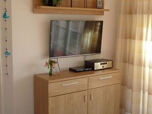 Un mueble de madera con un televisor de pantalla plana y una radio encima.