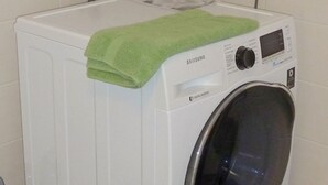 Un lave-linge Samsung à chargement frontal, avec une serviette verte posée sur le dessus.