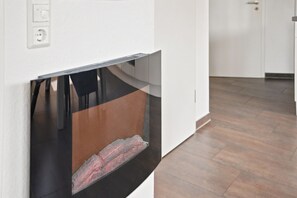Una cocina moderna con horno empotrado, pared blanca y suelo de madera.