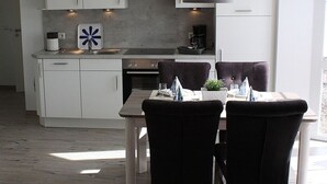Une cuisine moderne avec des meubles blancs, un îlot central et un coin repas équipé de deux chaises.