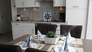 Un coin repas avec une table dressée pour quatre personnes, agrémentée d’un centre de table, d’assiettes, de couverts et de serviettes.