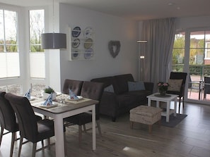 En hyggelig stue med en sofa, et spisebord dækket til fire personer og et lille sofabord.