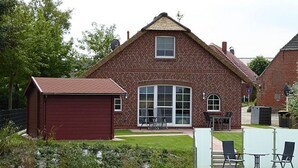 A brick building with a large window and a small attached shed. - Riedhaus am Siel - 100sqm vacation home for 6 pers. + dog with fireplace, heat cabin & (Krummhörn)