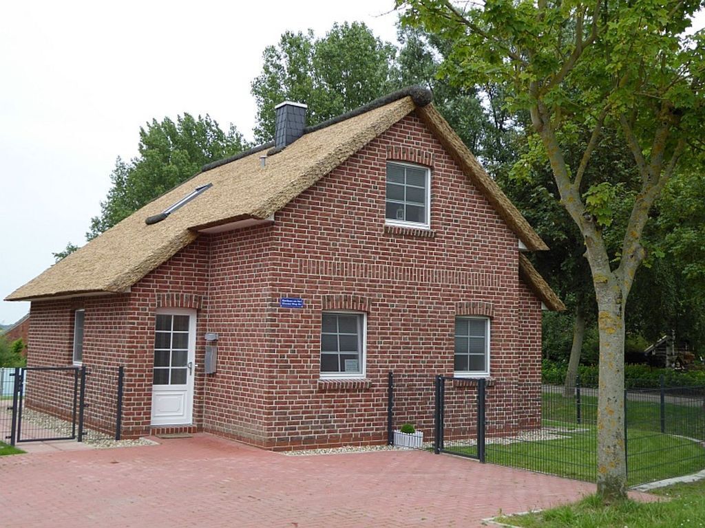 A brick building with a thatched roof, a white door, and a small window.
