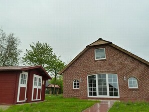 Un bâtiment en briques doté d’une grande fenêtre et d’une petite structure adjacente.