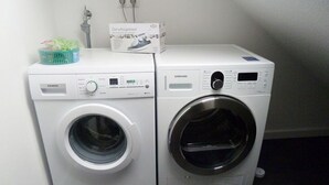 Two stacked washing machines in a laundry room. - Riedhaus am Siel - 100sqm vacation home for 6 pers. + dog with fireplace, heat cabin & (Krummhörn)