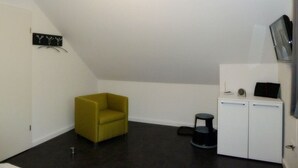 A small, modern room with a yellow armchair, a white cabinet, and a black stool. - Riedhaus am Siel - 100sqm vacation home for 6 pers. + dog with fireplace, heat cabin & (Krummhörn)