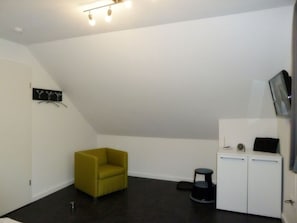 A small, modern room with a yellow armchair, a white cabinet, and a black stool.