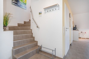 A staircase with a handrail, a small plant, and a wall-mounted shelf with a postcard. - Windrose - Beautiful, comfortable apartment in the best location of Greetsiel (Krummhörn)