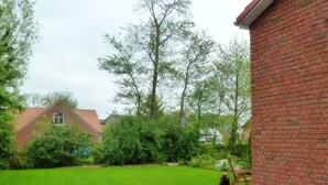 Un bâtiment en briques doté d’une terrasse pavée et d’une pelouse.