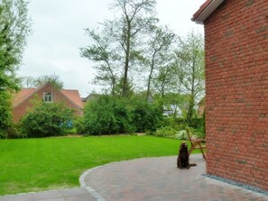 A brick building with a paved patio and a lawn.