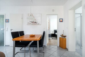 Un comedor moderno con una mesa de madera y sillas negras, una lámpara colgante y un cuadro en la pared.