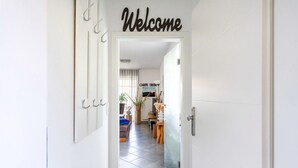 Un pasillo con un cartel de 'Welcome', un póster que dice 'Carpe Diem' y una vista de una sala de estar con un sofá y una mesa de centro.