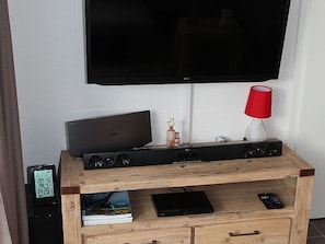A wooden entertainment unit with a flat-screen TV, a sound system, and a remote control.