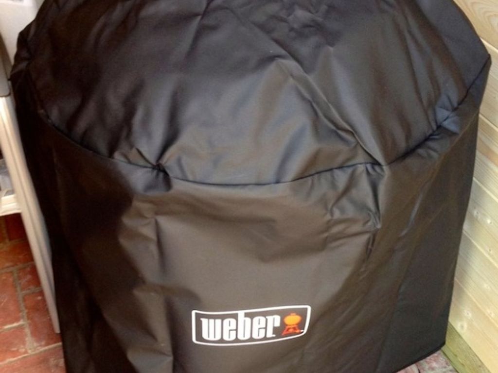 A black Weber grill cover with a logo.