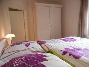A bedroom with a bed, a wardrobe, and a nightstand with a lamp.
