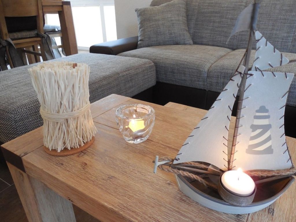Een houten tafel met een decoratieve kandelaar en een papieren bootje met een brandende kaars erin.