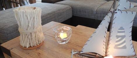 Een houten tafel met een decoratieve kandelaar en een papieren bootje met een brandende kaars erin.