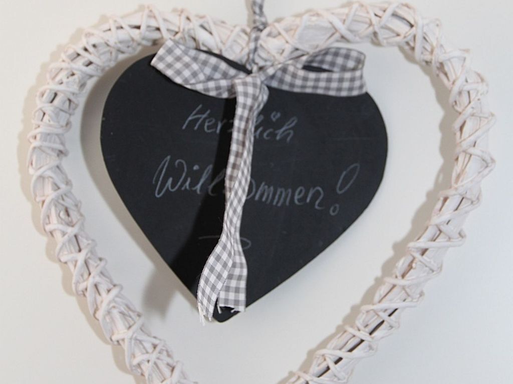 A heart-shaped chalkboard with a checkered ribbon bow, surrounded by a woven frame.