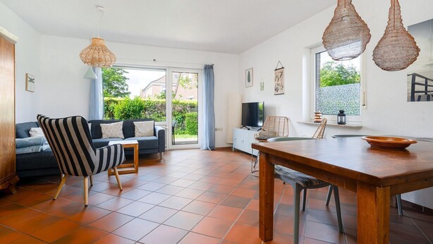 Ein geräumiger Wohnbereich mit Sofa, gestreiftem Sessel und Esstisch.