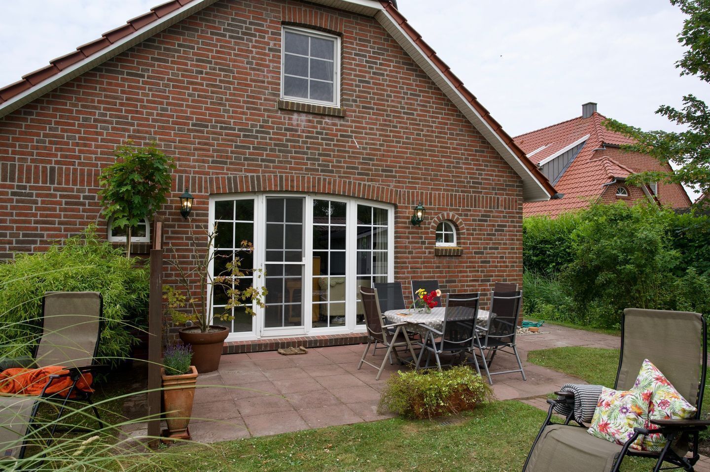 Ein Ziegelhaus mit Terrasse, einem Esstisch und Gartenstühlen.