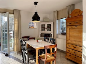 Ein Essbereich mit Tisch, Stühlen, einem Schrank und einem Fenster mit Vorhängen.