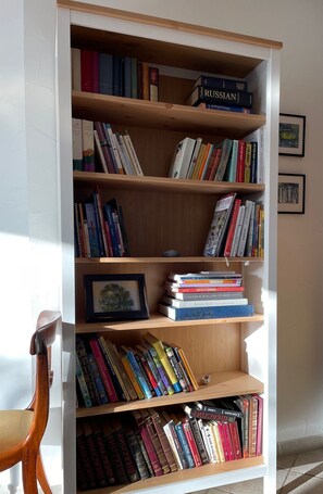 Una estantería con varios libros y un cuadro enmarcado.