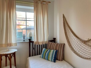 Une chambre à coucher avec un lit, une table de chevet, une lampe et un hamac.