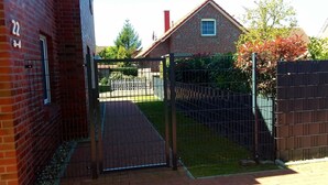 Een bakstenen gebouw met een metalen hekwerk dat uitkomt op een verhard gebied.