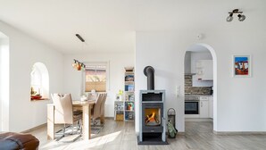 A modern living room with a fireplace, dining area, and kitchen. - Midsummer - Beautiful vacation home (100sqm) for 6 people with fireplace, garden and (Krummhörn)