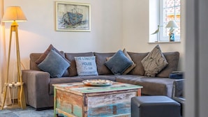 A cozy living room with a brown sofa, a coffee table, and a framed picture on the wall. - Fischhuus - Beautiful vacation home near the water (Krummhörn)