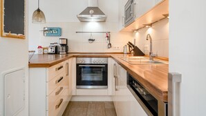 A compact kitchen with a built-in oven, a microwave, and a sink. - Fischhuus - Beautiful vacation home near the water (Krummhörn)