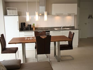 Uma cozinha moderna com uma mesa de jantar, cadeiras e uma máquina de café.