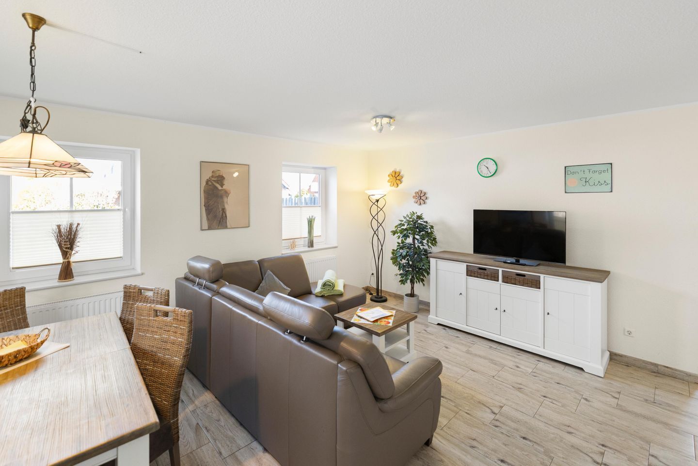 A modern living room with a sofa, TV, dining table, and decorative items.
