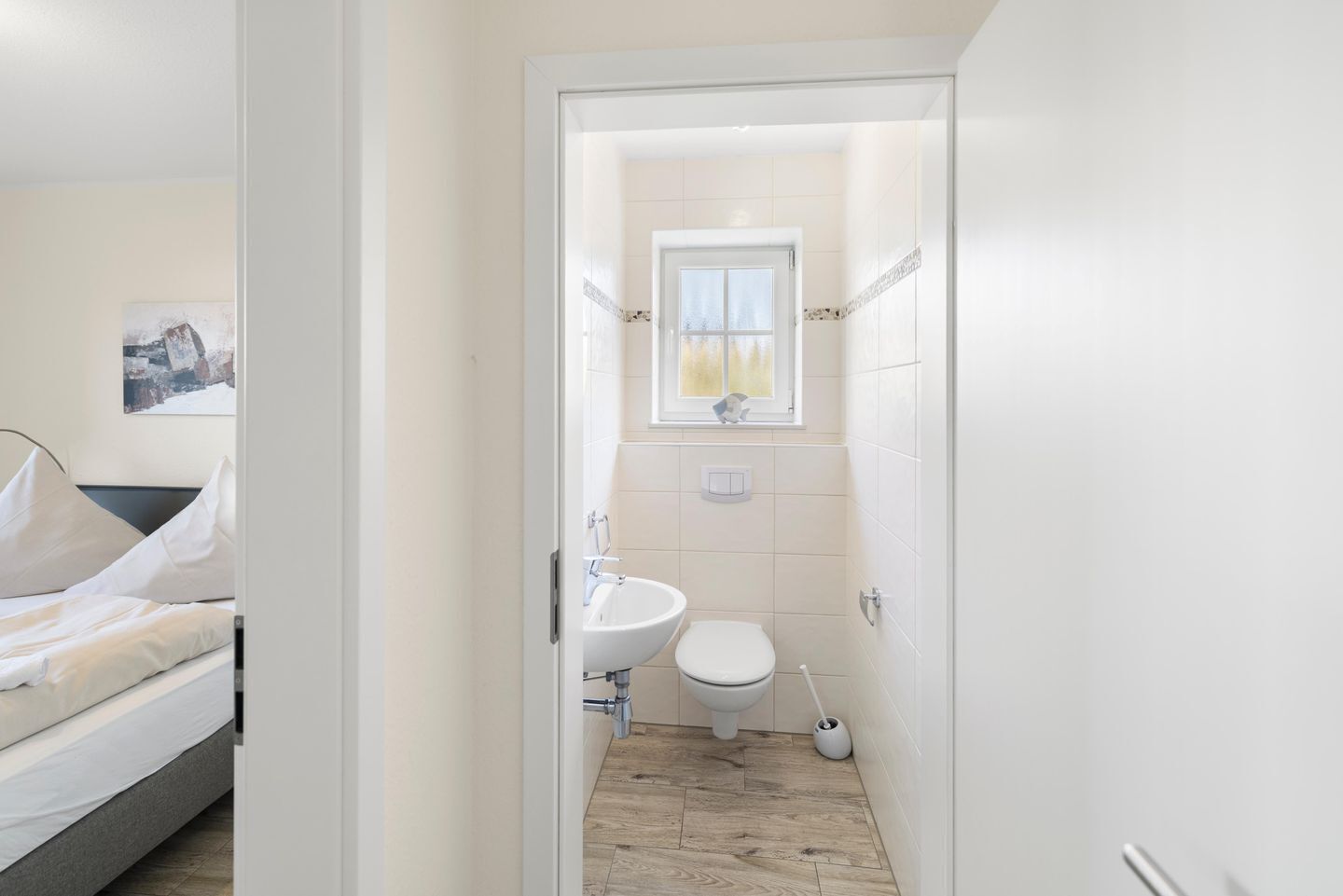 A small, clean bathroom with a toilet, sink, and window.