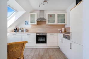 A modern kitchen with white cabinets, a built-in oven, and a coffee maker.