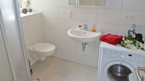 Un baño pequeño y limpio con inodoro, lavamanos y lavadora.