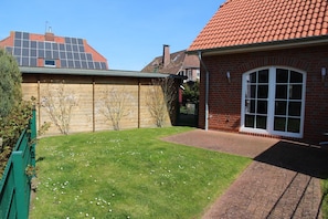 A residential backyard with a lawn, a brick house, and a wooden fence. - Sieloase - End terraced house in a quiet location with water access (Krummhörn)