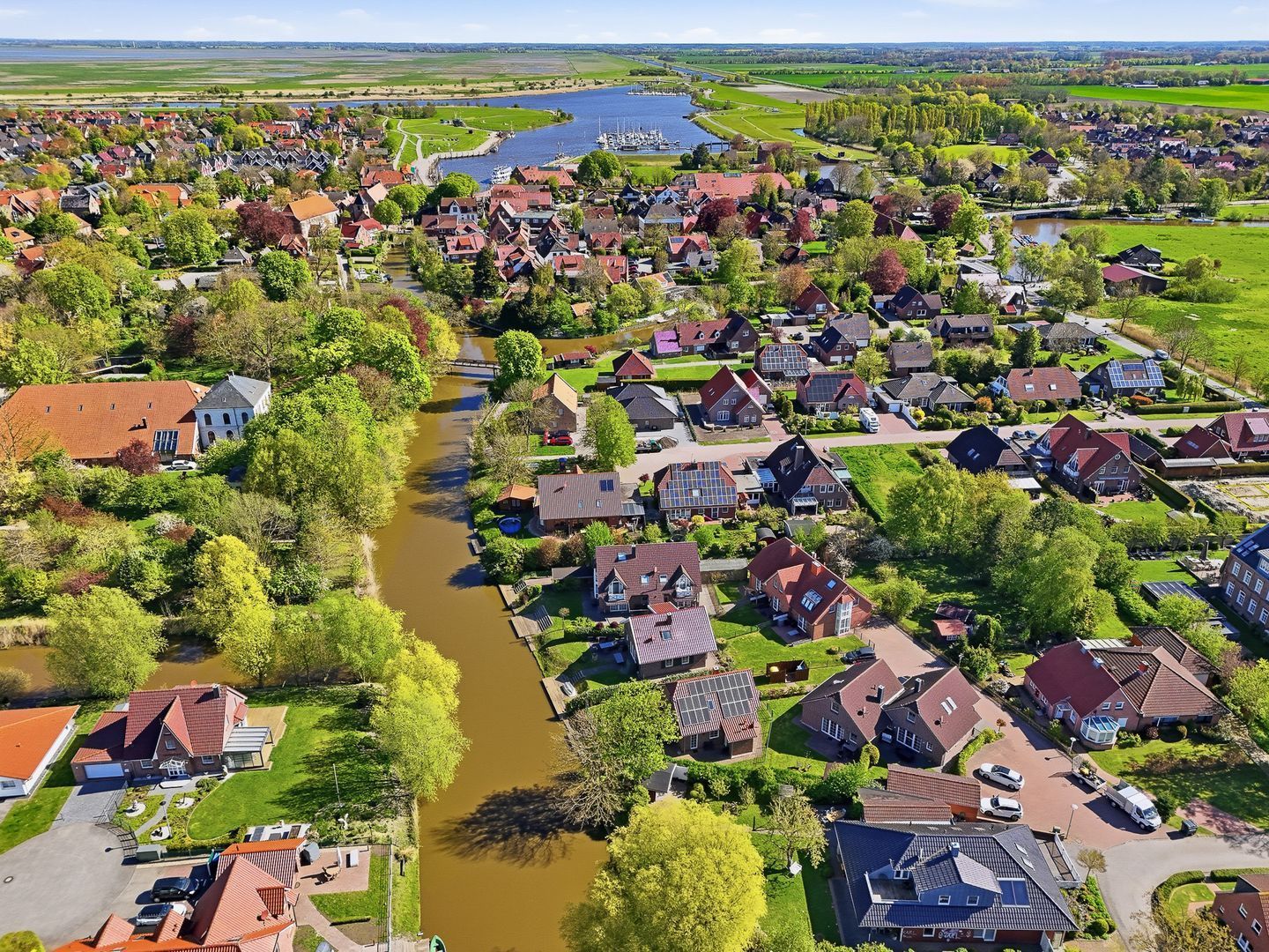 An aerial view of a residential area with houses, a river, and a marina.