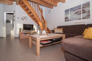 Una sala de estar con una escalera de madera, un televisor, un sofá y una mesa de centro.