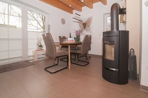 Un comedor con mesa, sillas, chimenea y ventana.