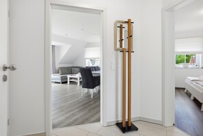 Un intérieur moderne avec un porte-manteau en bois, un canapé gris et un coin repas.