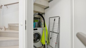A laundry room with a washing machine, a drying rack, and a step with a handrail.