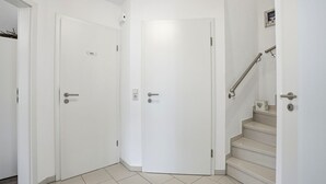 A hallway with two white doors, one marked 'Toilet,' and a staircase with a handrail.
