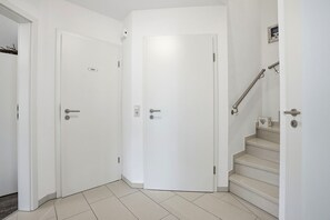 A hallway with two white doors, one marked 'Toilet,' and a staircase with a handrail.