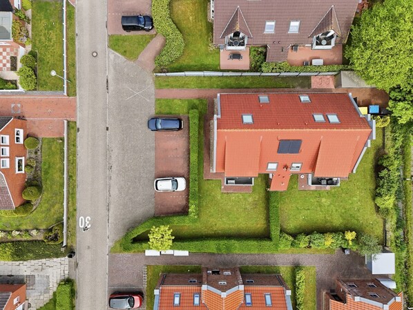 An aerial view of a residential area with houses, a street, and parked cars.